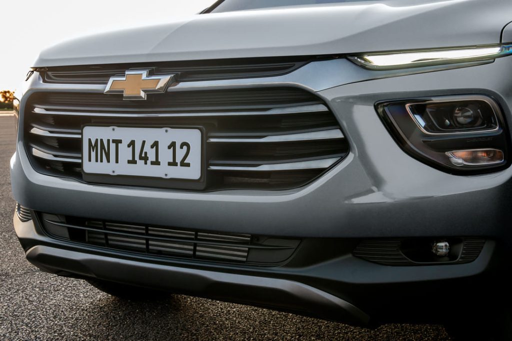 Frente de um carro Chevrolet prata, com destaque para a grade, faróis modernos e o logotipo dourado da marca.