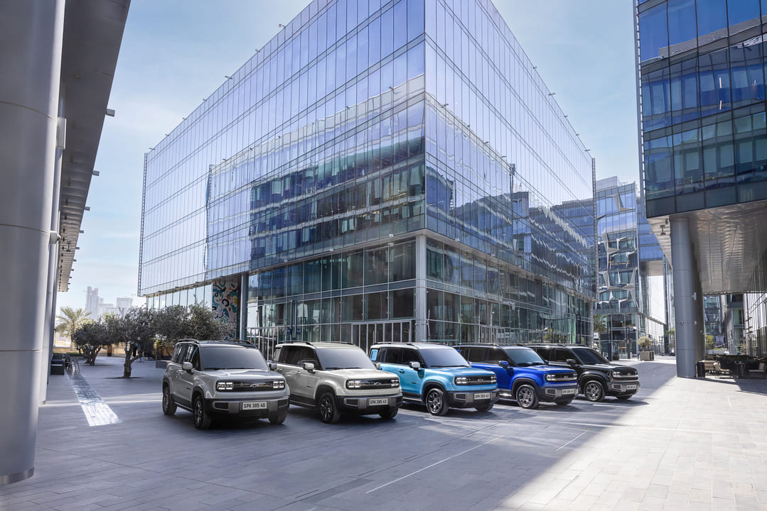 Linha de SUVs Chevrolet estacionados em frente a um moderno prédio comercial espelhado.