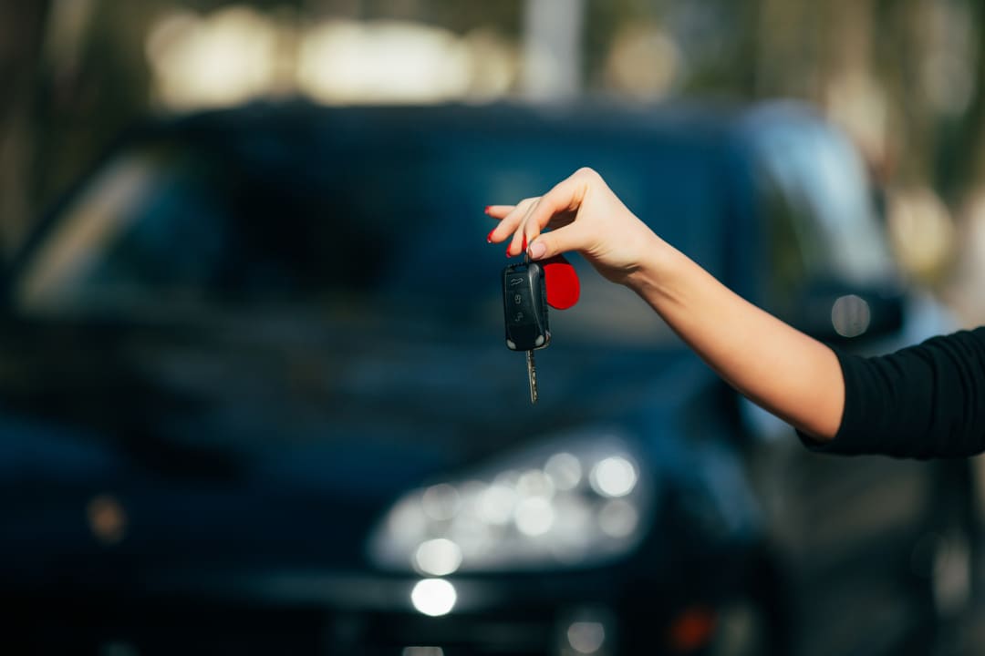 Mulher segurando uma chave ao comprar um carro seminovo.