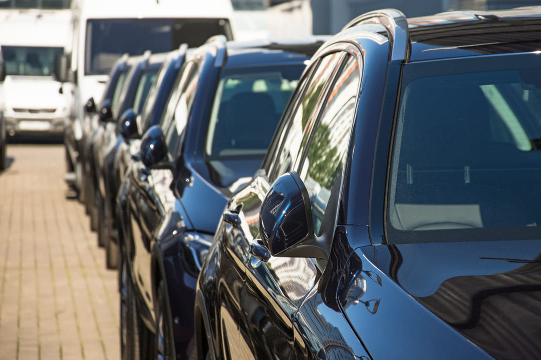 Fila de veículos SUV novos estacionados em pátio comercial, representando opções de carros para empresas com CNPJ.
