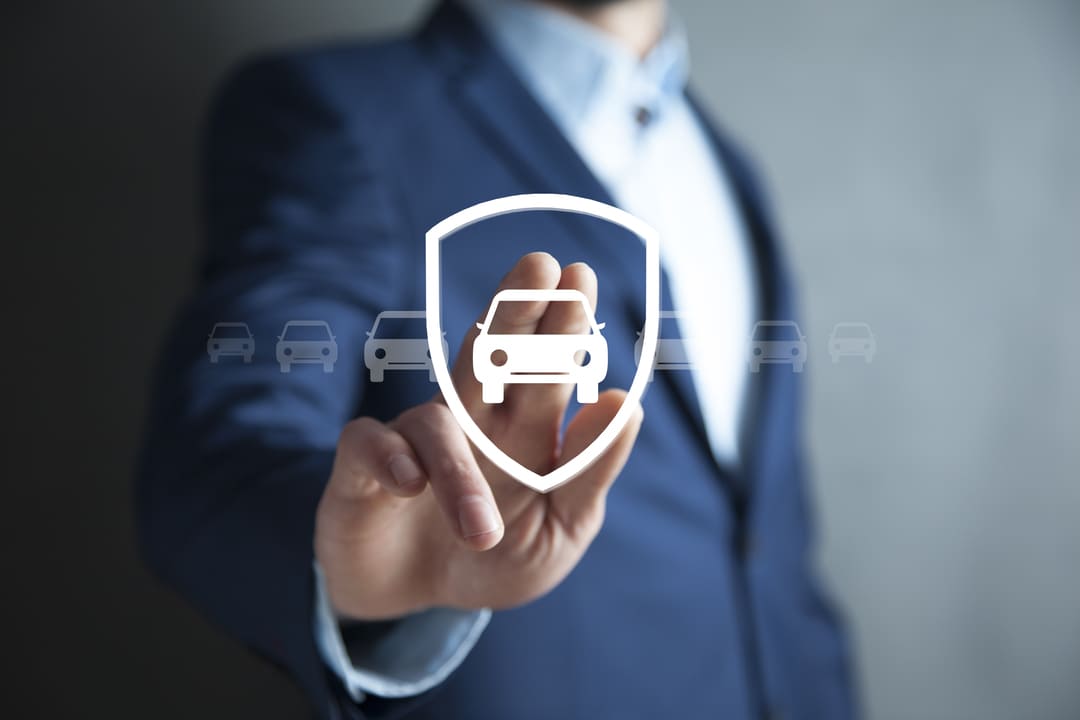Homem de terno tocando ícone de carro com escudo, representando proteção veicular, conceito de como funciona a garantia de carros usados em negociações e revendas.
