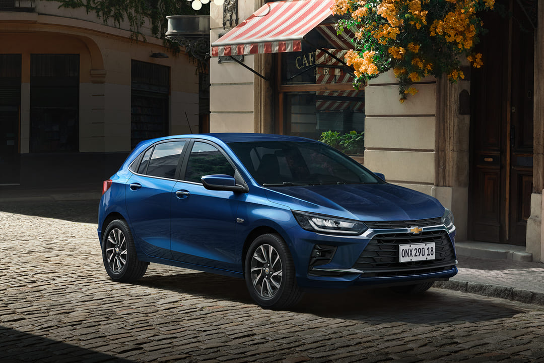 Chevrolet Onix 2026 na cor azul estacionado em rua de paralelepípedos, mostrando design atualizado e moderno.