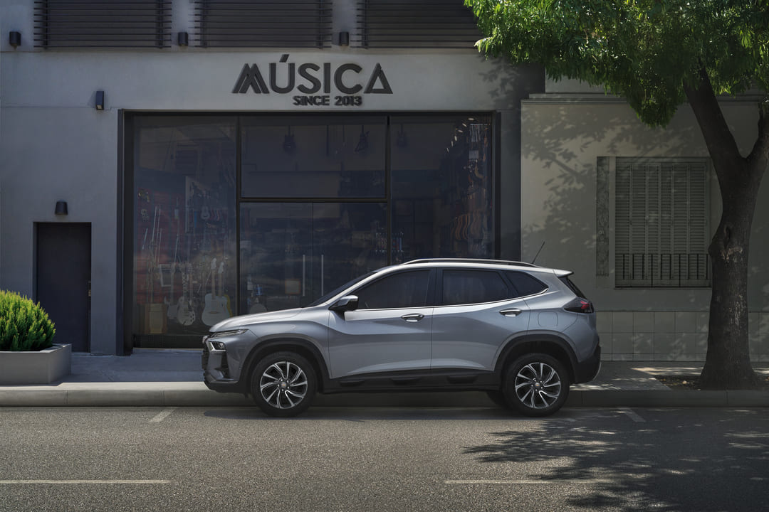 Chevrolet Tracker 2026 prata estacionado em frente a loja de instrumentos musicais com fachada cinza.