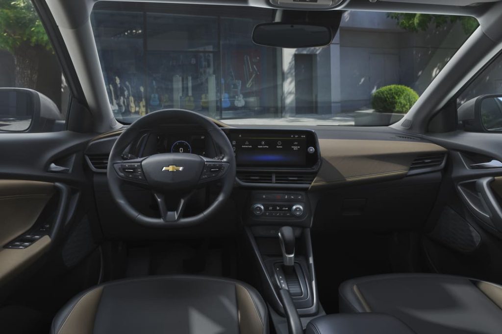 Interior do Chevrolet Tracker 2026 com volante multifuncional, central multimídia e acabamentos em preto e marrom.