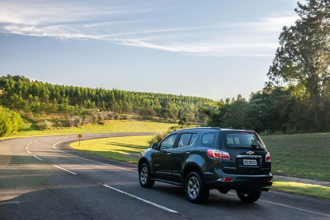 Carro para família em uma estrada rodeada por árvores e natureza, transmitindo conforto e segurança para viagens.